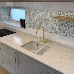 Patterned wall tiles and gold taps in this kitchen refurbishment by Thomson Properties