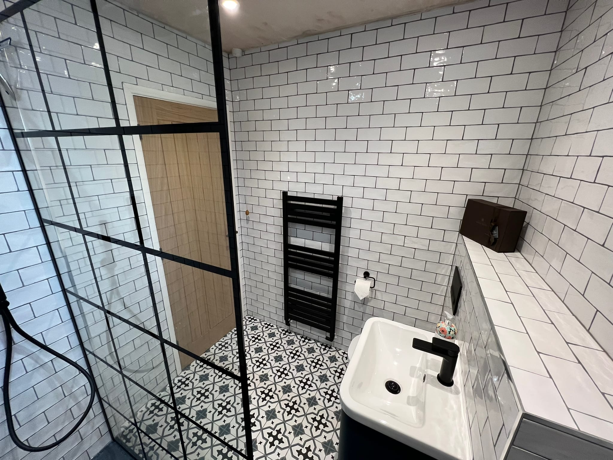 Monochrome bathroom with patterned floor tiles, brick wall tiles and black fittings