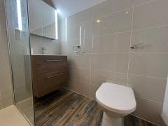 En suite bathroom refurbishment with illuminated mirror and large wall tiles, Thomson Properties,  Cranleigh