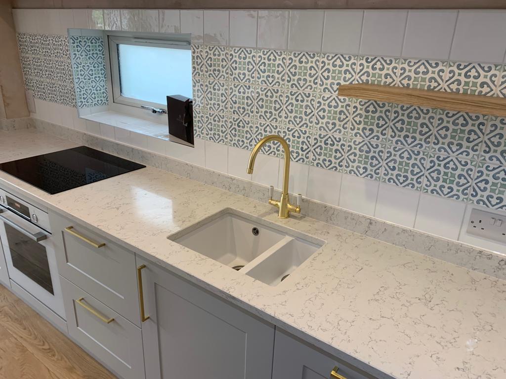 Patterned wall tiles and gold taps in this kitchen refurbishment by Thomson Properties